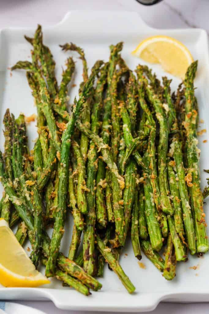 cooked asparagus on a platter with breadcrumbs and parmesan cheese