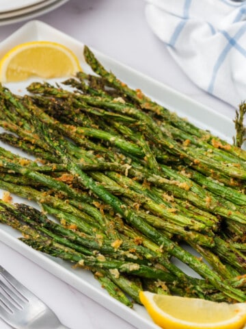 air fryer asparagus on a platter with lemon wedges
