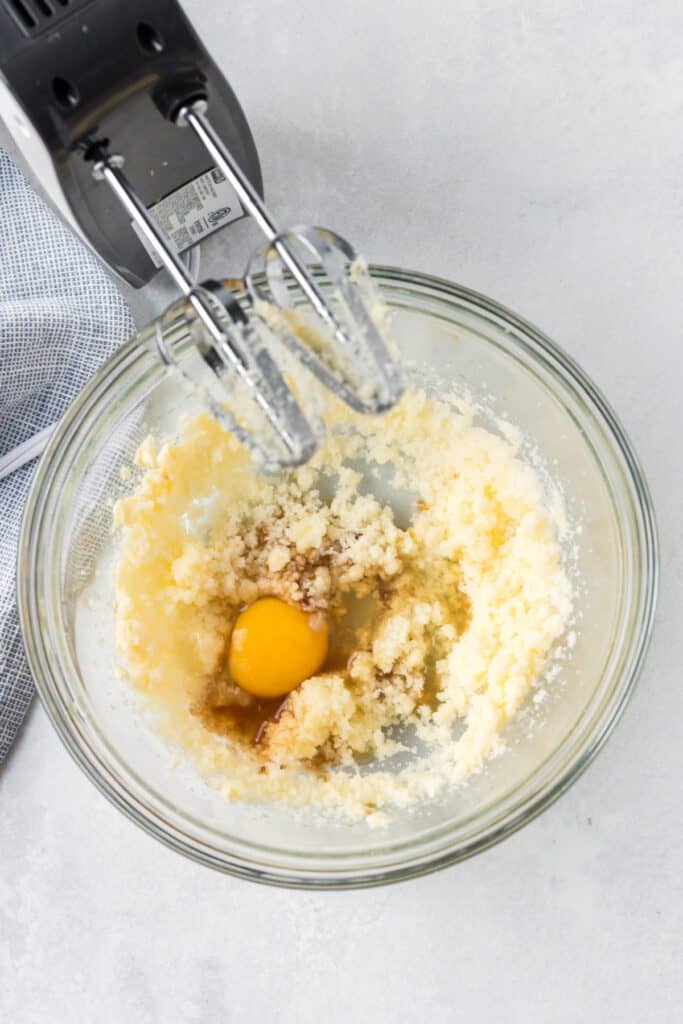 Sugar, butter and eggs in a bowl with an electric mixer.