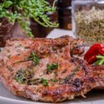 A bone in pork chop cooked, on a plate for serving.