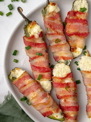 Bacon wrapped jalapeno poppers on a plate.