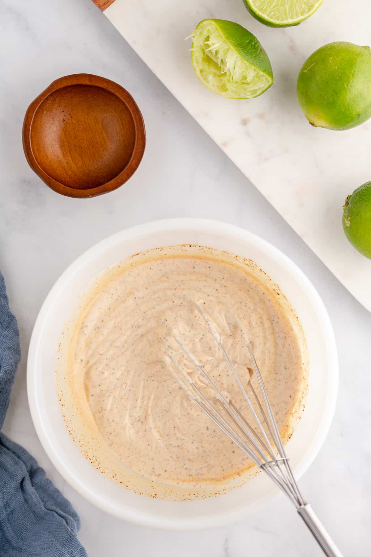 Whisked chipotle mayo sauce with lime halves on the side.