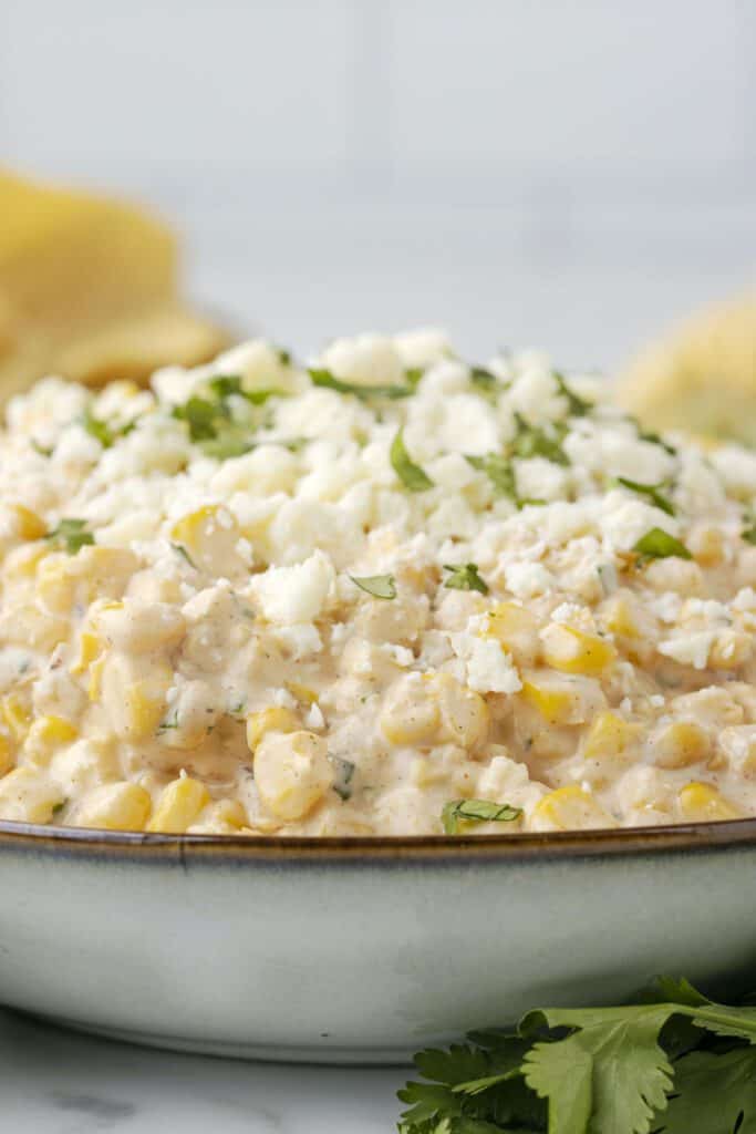 Creamy sweet corn dip topped with white cheese and cilantro.