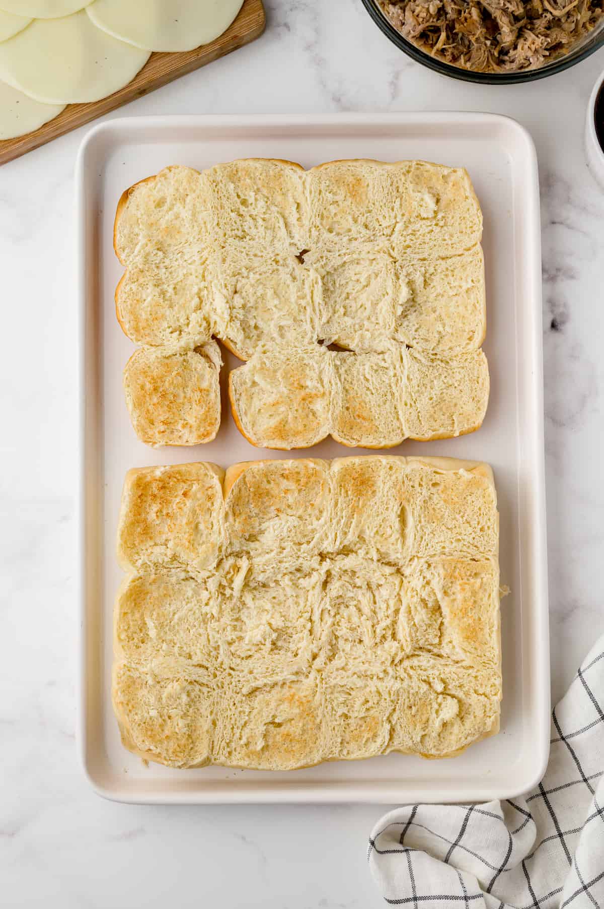 Toasted slider buns on a rimmed baking sheet.