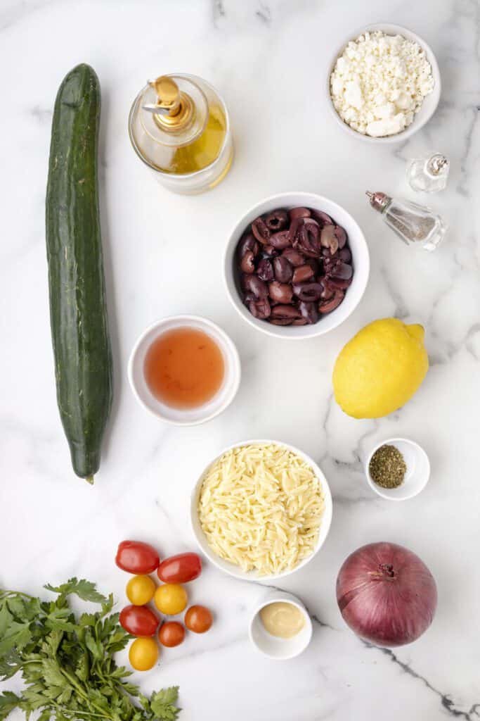 Ingredients in a Greek pasta salad with orzo, cucumber, feta and tomatoes.