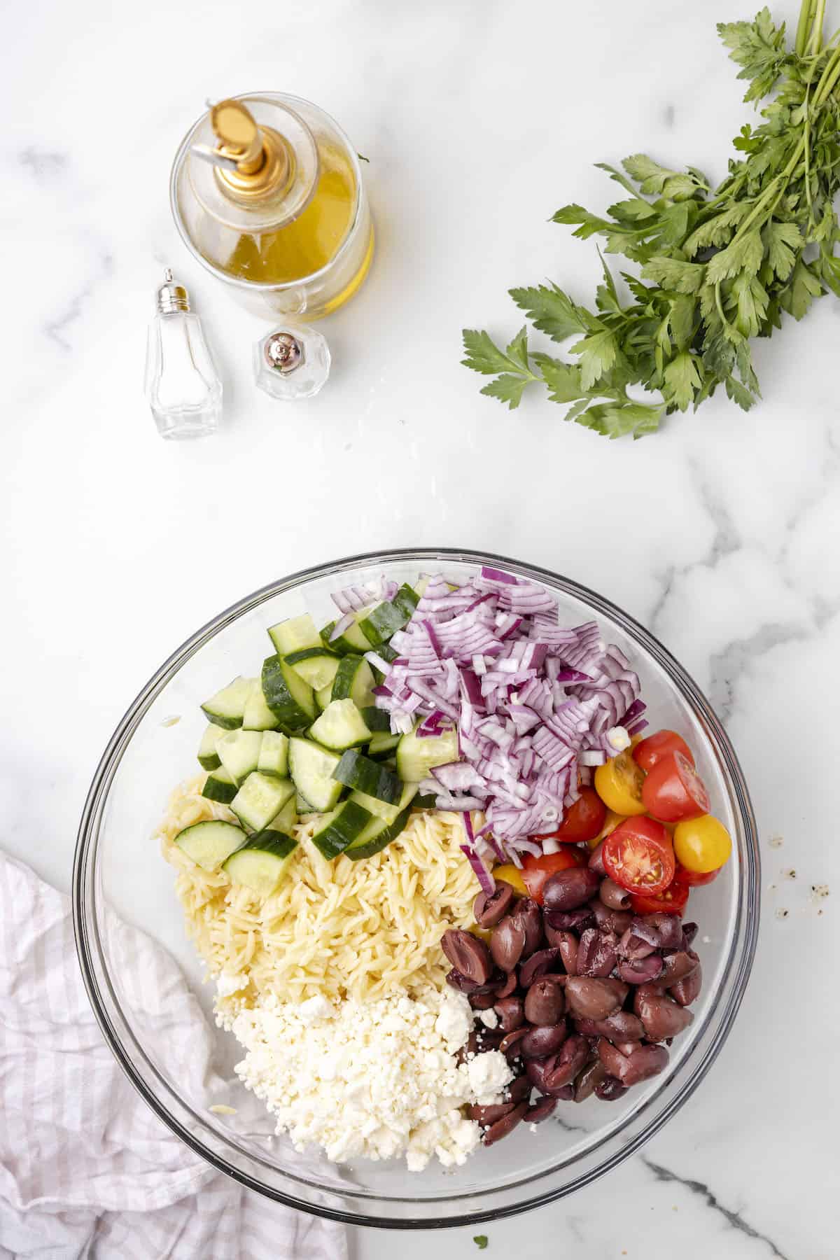 Lemon orzo salad ingredients in a large glass bowl.