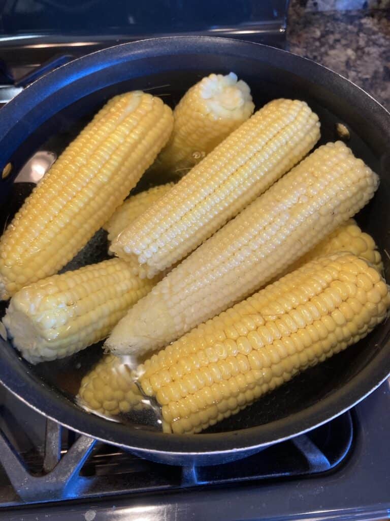 Corn on the cob in a pot of boiling water.