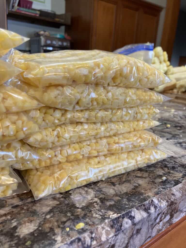 Bags of sweet corn to be frozen sitting on a countertop.