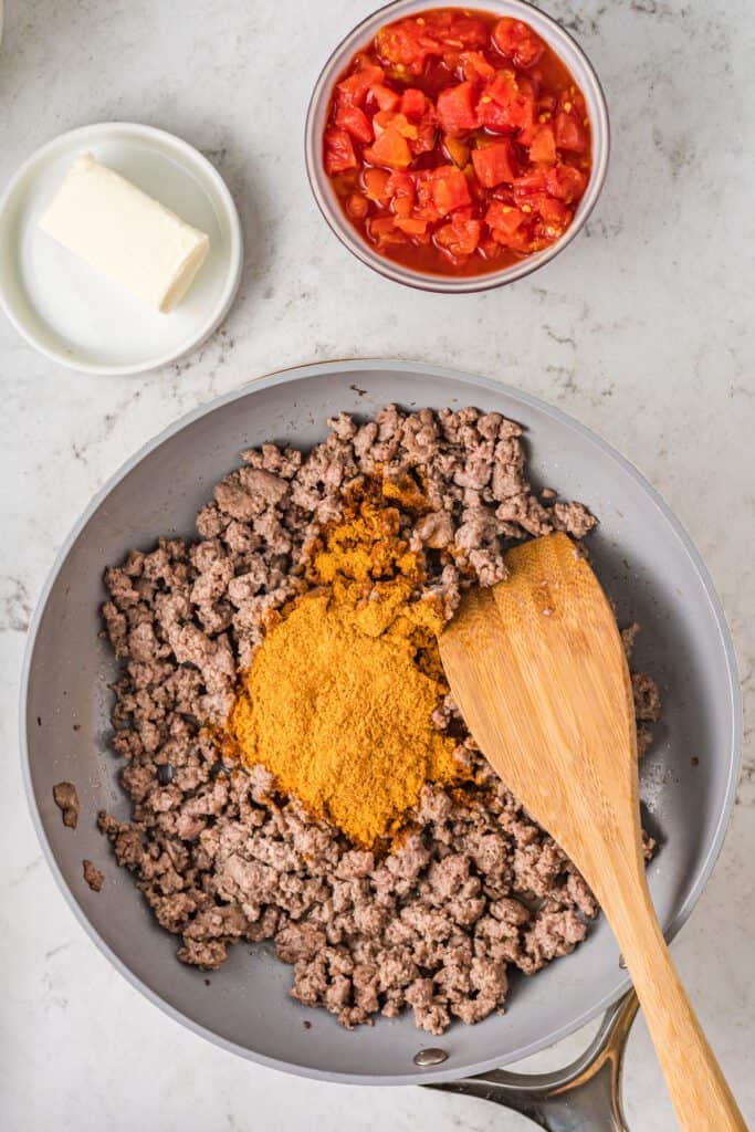 Cooked ground beef in a skillet with taco seasoning.