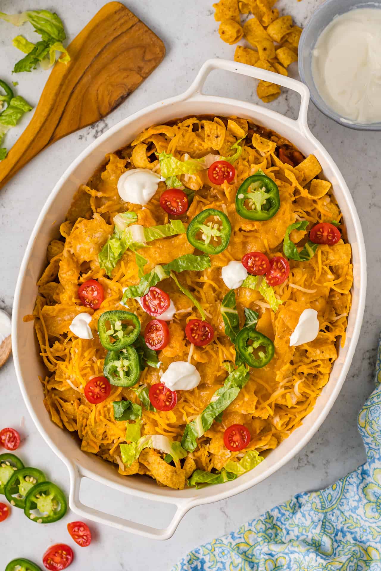 Walking taco casserole topped with dollops of sour cream and jalapeno slices.