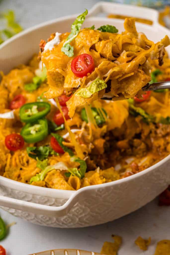 Walking taco casserole in a dish with a large spoon.