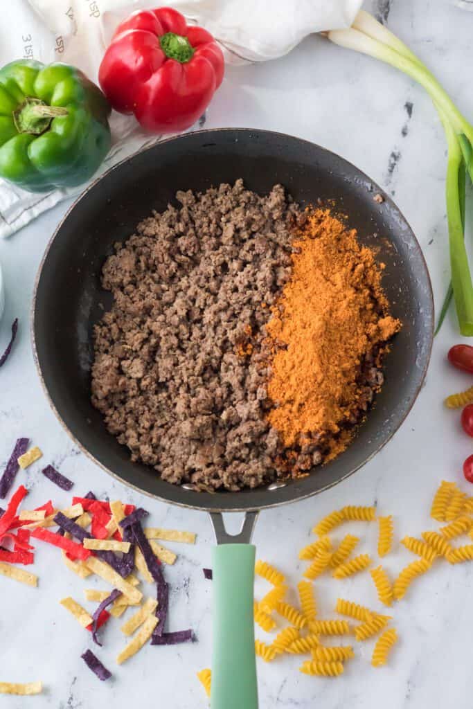 Cooked ground beef in a skillet with taco seasoning.