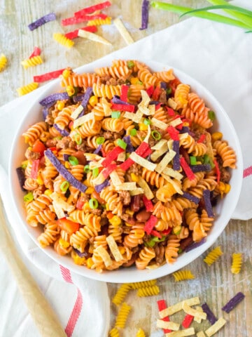 Taco pasta salad in a serving bowl with colored tortilla strips.