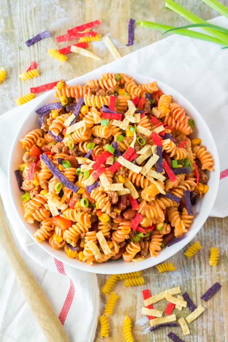Taco pasta salad in a serving bowl with colored tortilla strips.