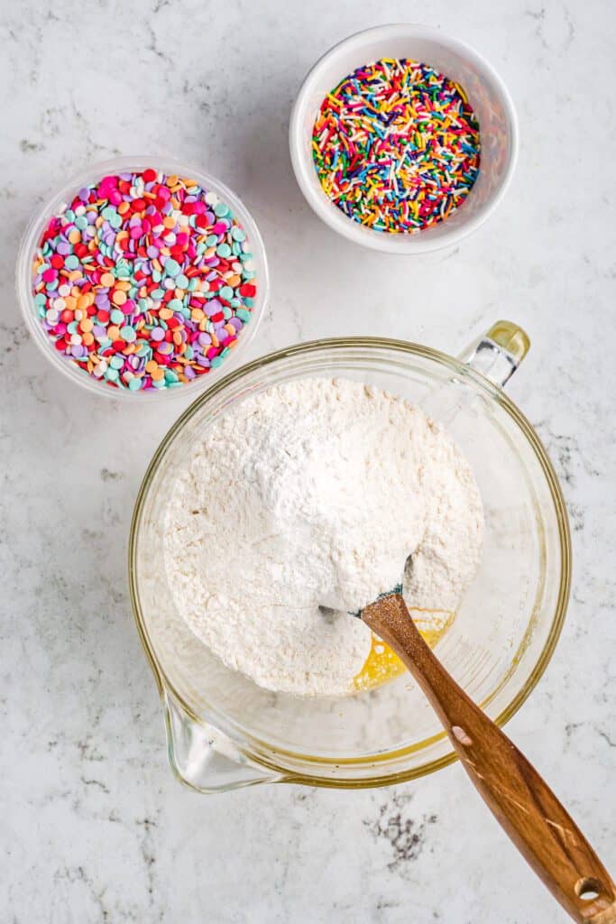 Cake mix in a bowl with sprinkles in a bowl alongside.