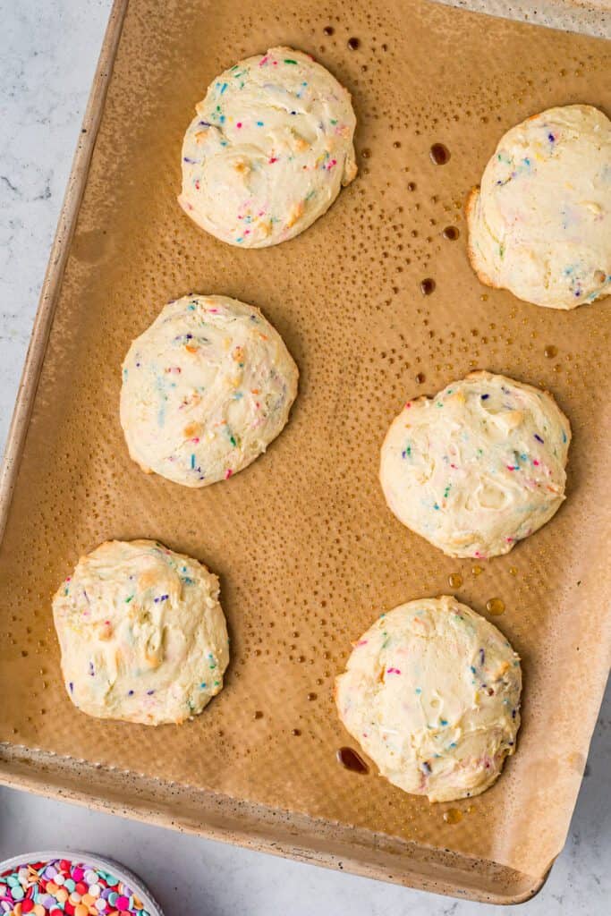 Baked funfetti cookies on a parchment covered cookie sheet.