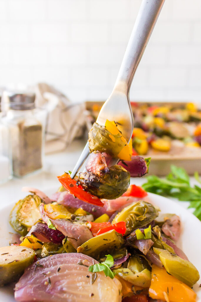 Roasted brussels sprouts, red onion and bell pepper on a fork.