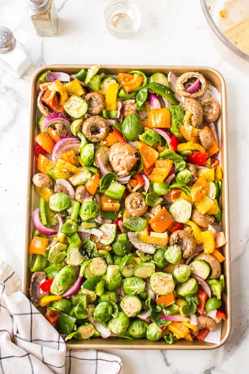 A sheet pan full of seasoned and chopped vegetables.