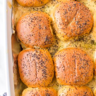 Roast beef sliders topped with poppy seeds in a casserole pan.