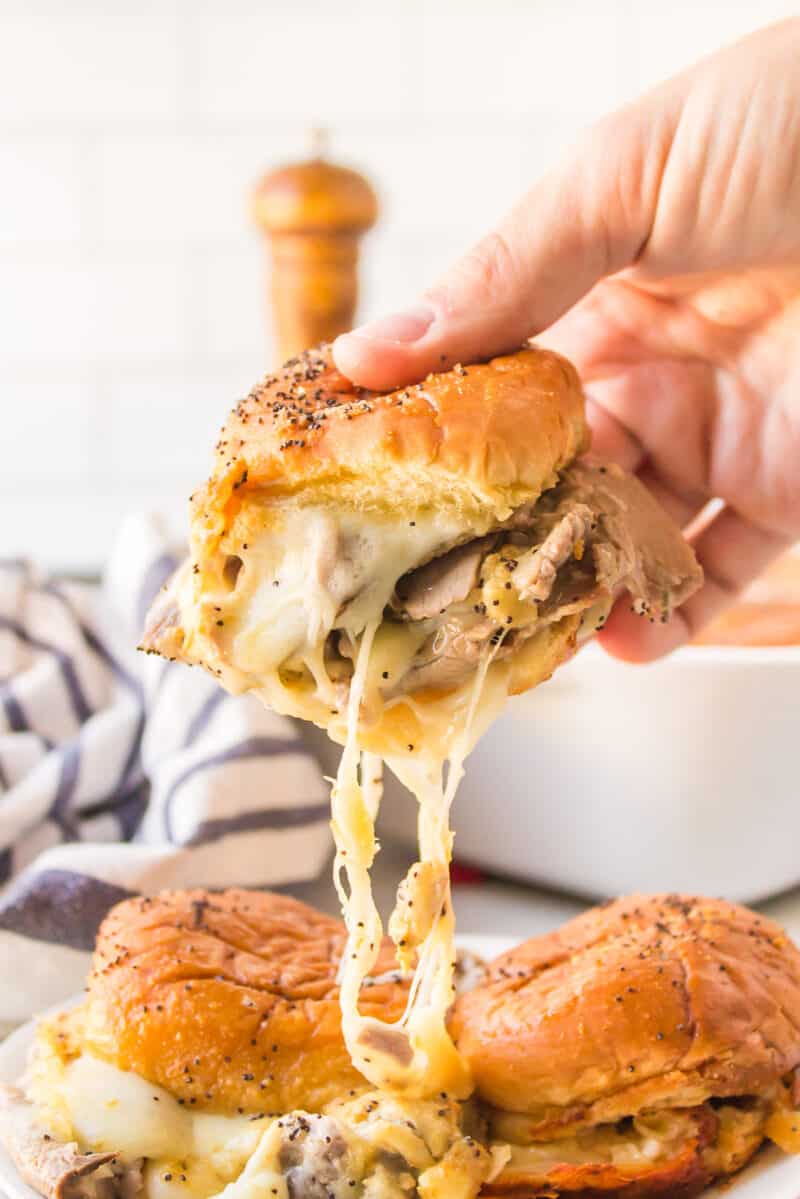 Pulling apart a cheesy Hawaiian Roll Roast Beef Slider with melted provolone.