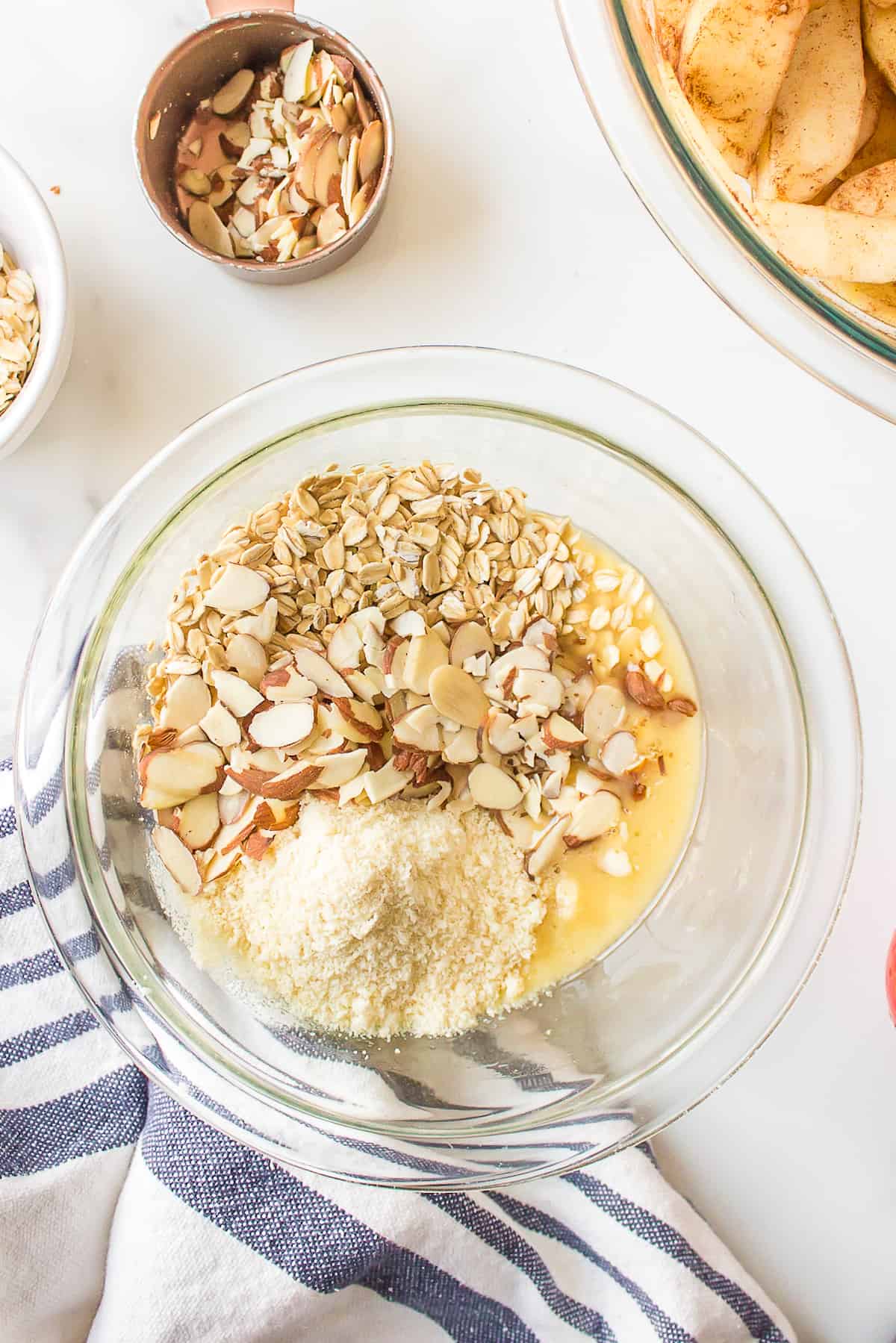 Almond flour, eggs, slivered almonds and rolled oats in a mixing bowl.