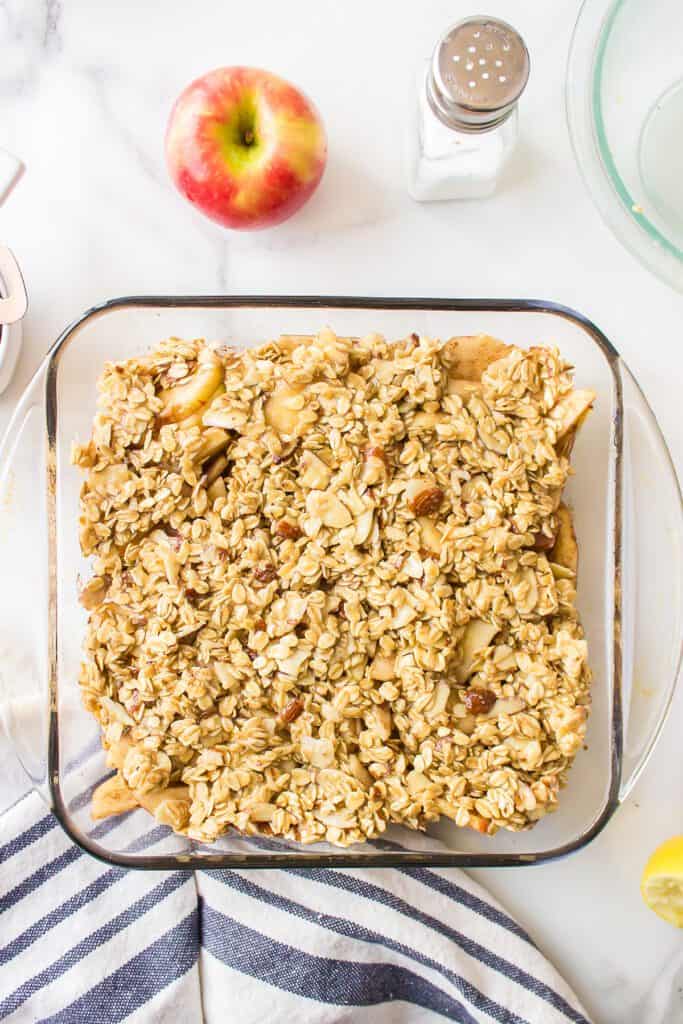 Oatmeal topped apple crisp in a square baking pan.