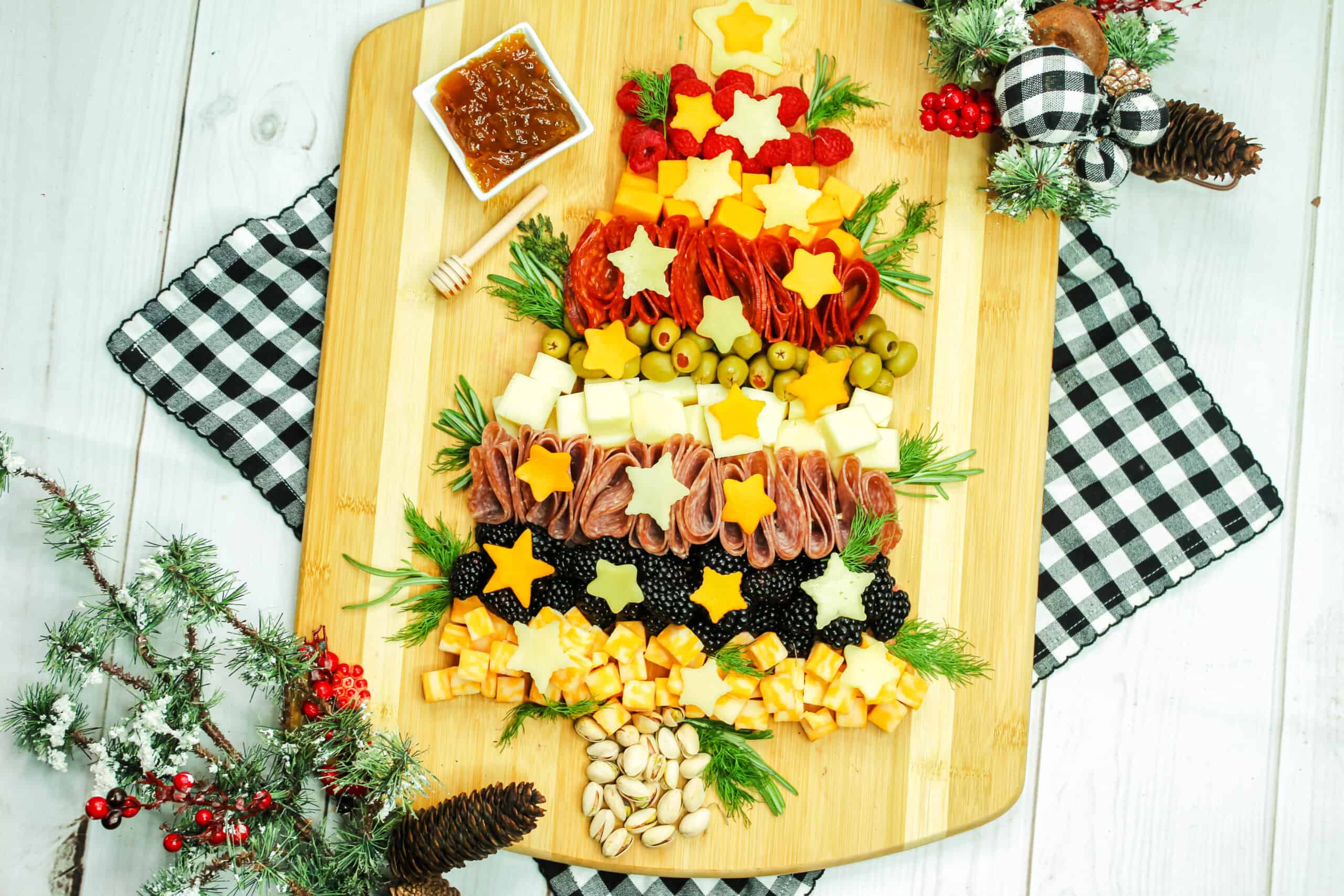 Christmas tree appetizer board with cheese, meat, and berries.