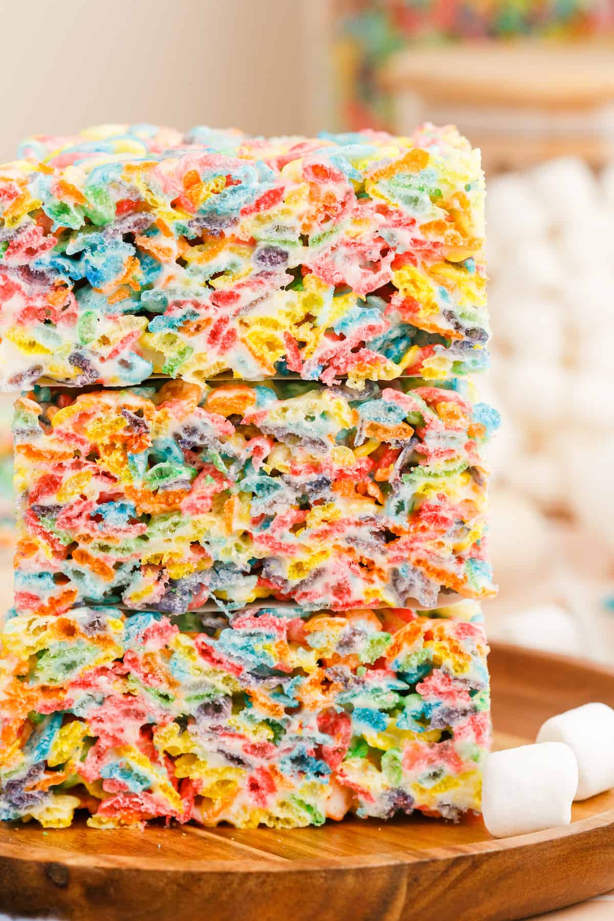 A close up of rainbow colored rice krispie treats with fruity pebbles cereal.