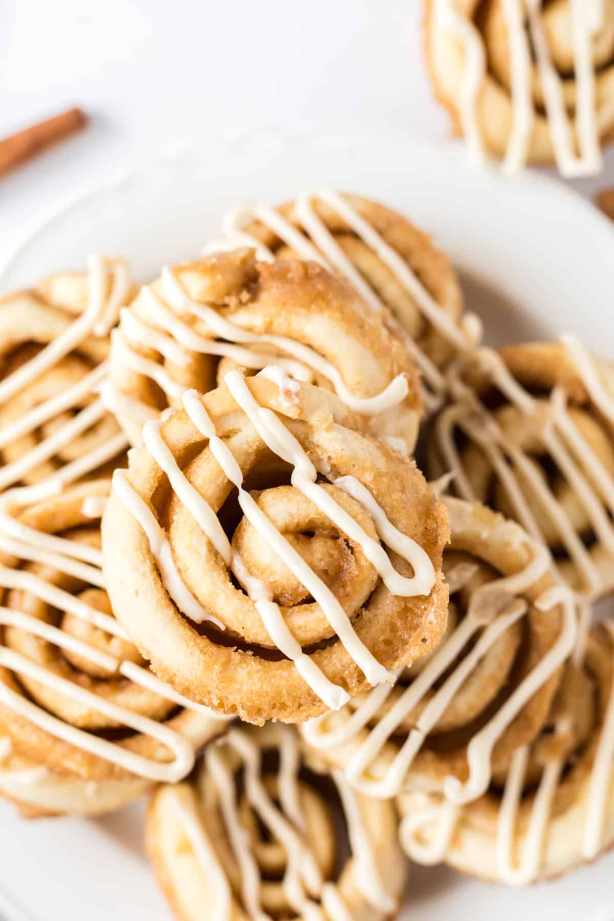 Stacked cinnamon roll swirl muffins topped with icing on a plate.