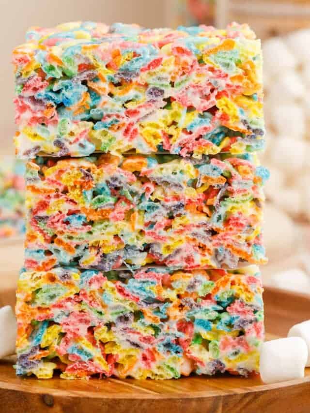 A stack of fruity pebbles rice krispie treats on a wooden plate.