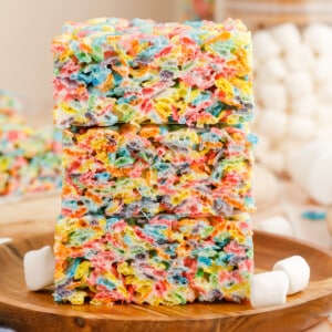 A stack of fruity pebbles rice krispie treats on a wooden plate.