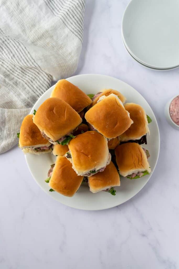 A stack of ground turkey sliders with cranberry mayo on a plate.