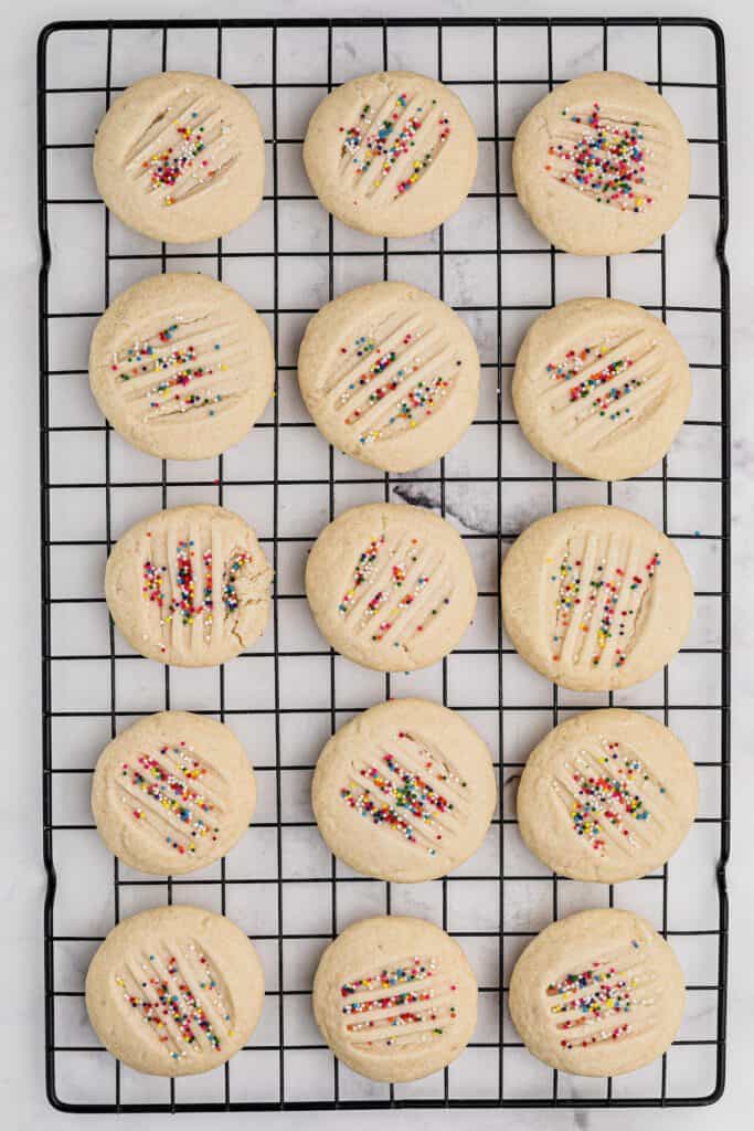 Sprinkle topped shortbread cookies on a cooling rack.