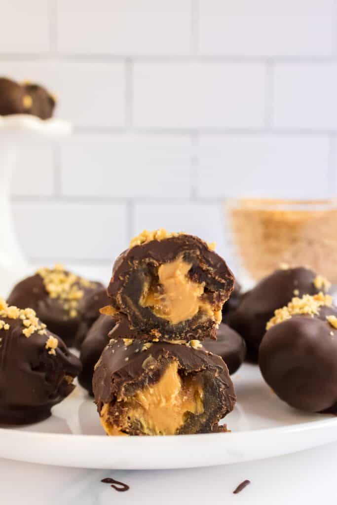 Peanut butter stuffed dates coated in chocolate on a plate.