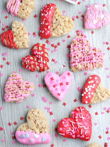 Heart shaped rice krispie treats colored with frosting on a counter.