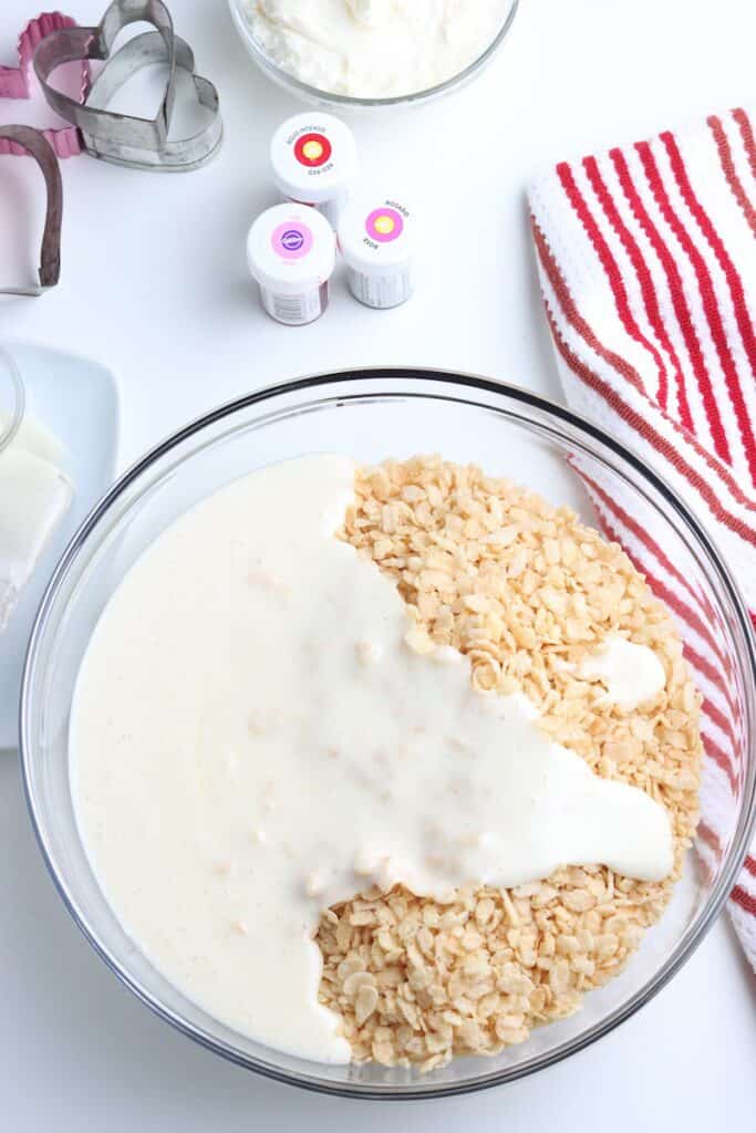 Rice krispie cereal topped with marshmallow mixture in a glass bowl.