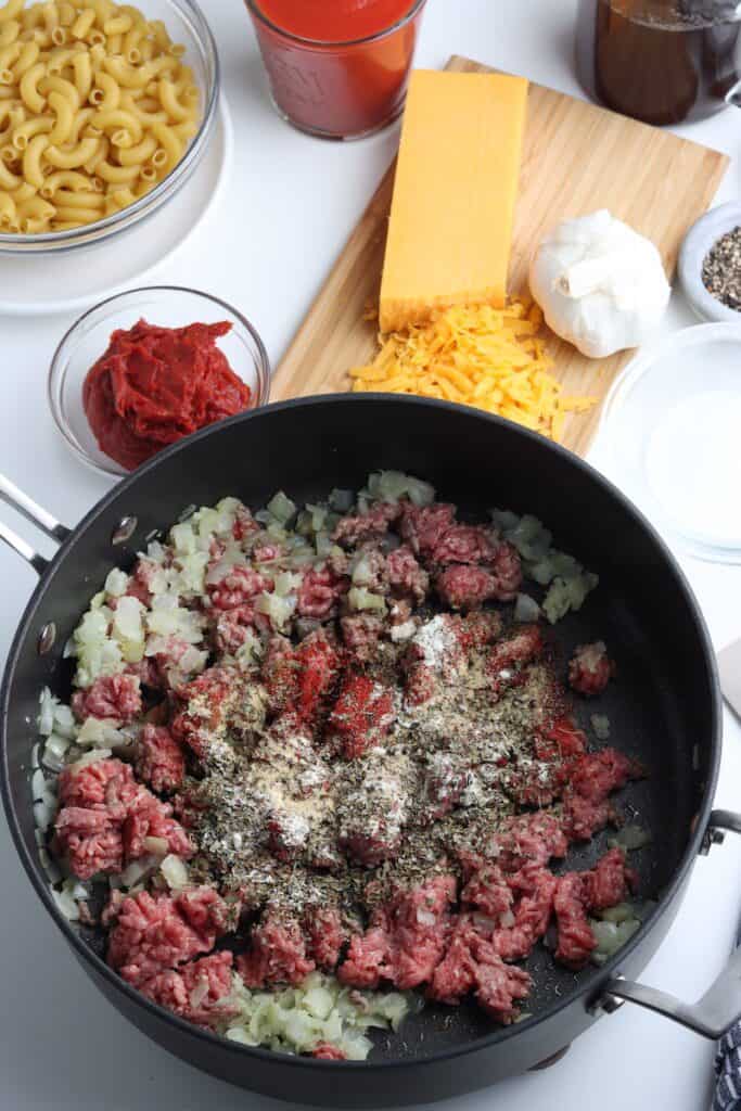 Onion, seasonings and ground beef in a skillet.