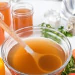 Vegetable broth in a bowl with a ladle.