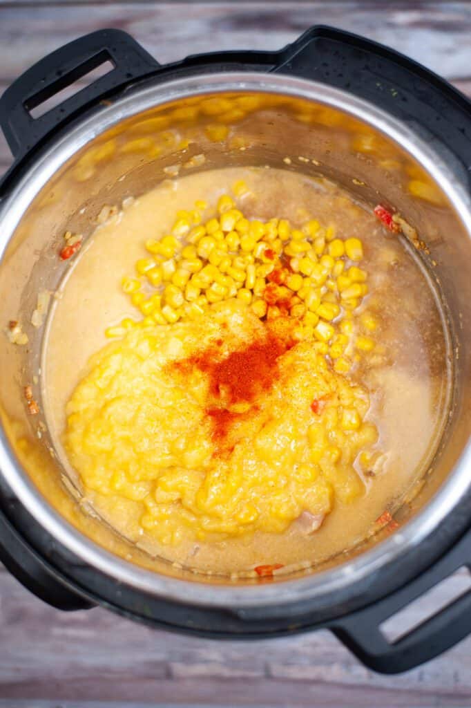 An instant pot with added  potatoes, corn, paprika, black pepper, and Worcestershire sauce. 