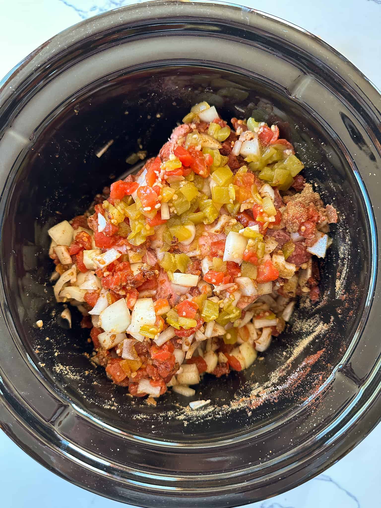 Adding onions, garlic, and spices to roast in slow cooker.