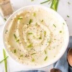 A bowl of mashed cauliflower topped with snipped fresh chives.