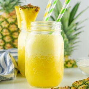 A mason jar filled with pineapple agua fresca and two straws.