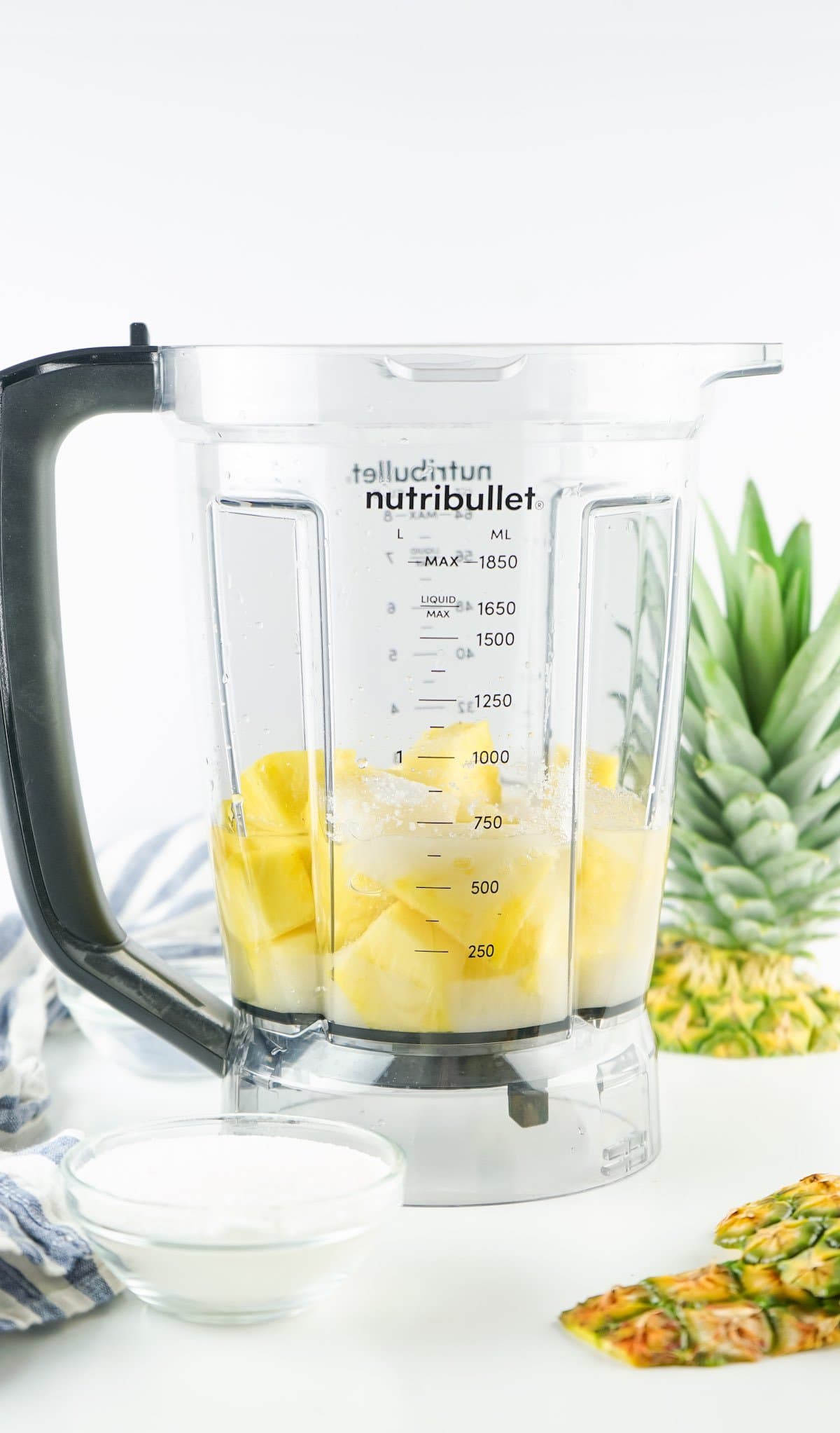 A high powered blender filled with the ingredients to make a pineapple drink.