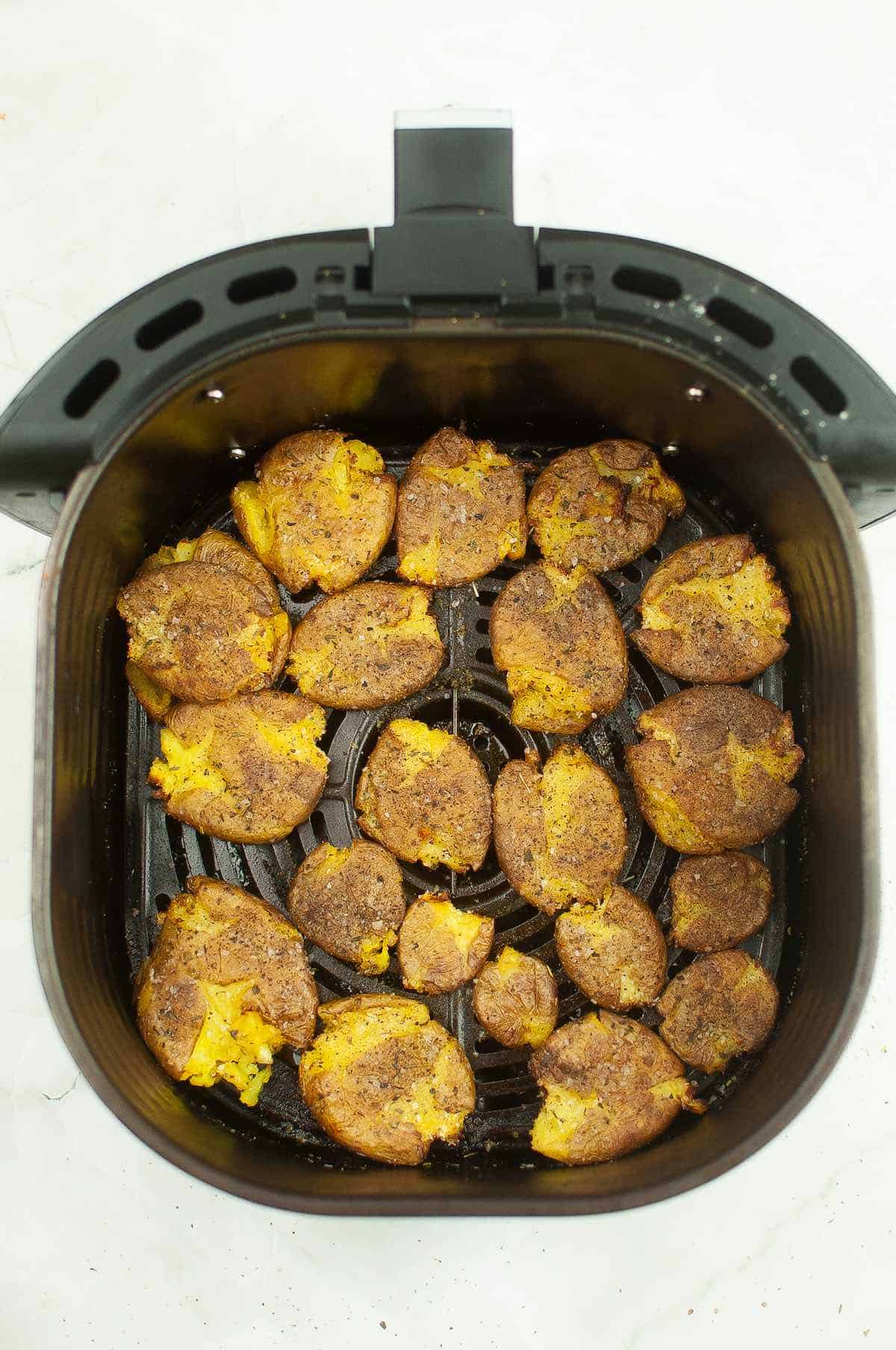 An air fryer basket of smashed potatoes.