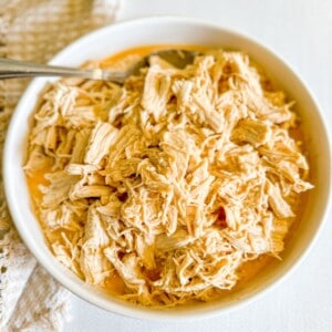 A bowl of shredded buffalo chicken with a fork in it.