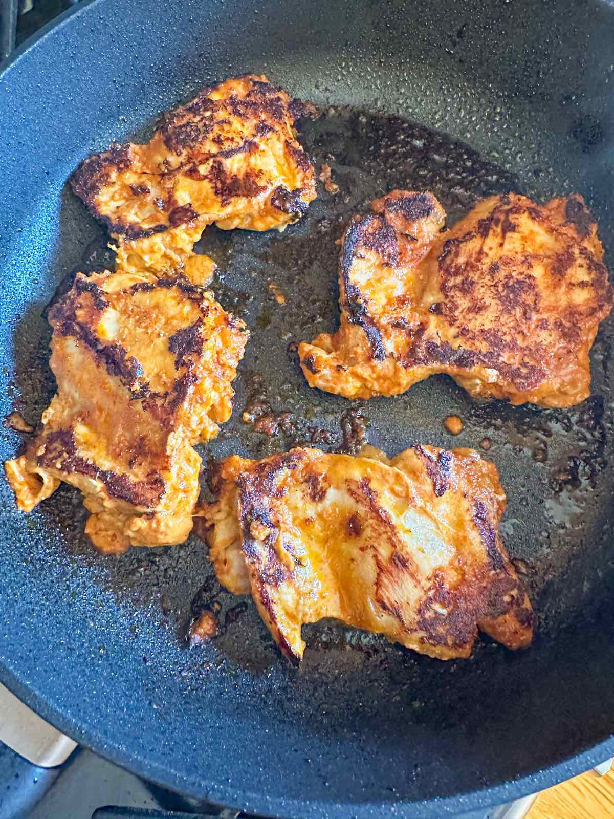 Chipotle chicken thighs in a skillet.