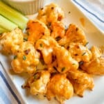 A platter of bite sized cauliflower coated in buffalo sauce.