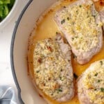 Parmesan crusted pork chops in an enamel coated skillet.