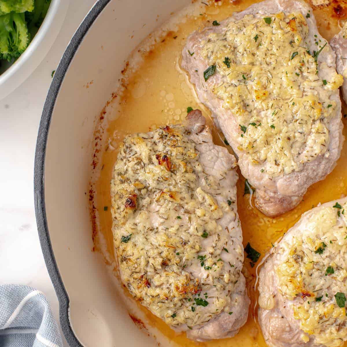 Parmesan crusted pork chops in an enamel coated skillet.