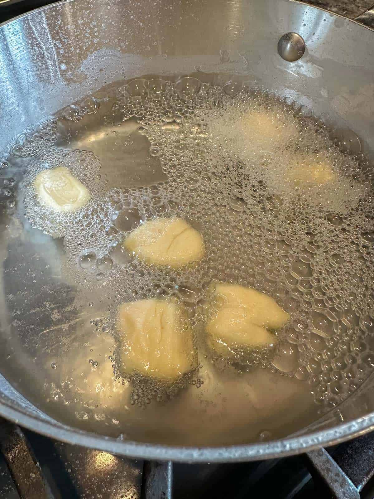 Dough bites in a pan of simmering water.